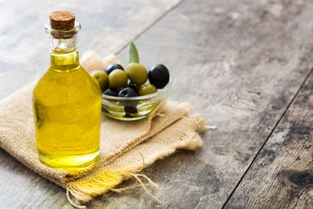 Virgin olive oil in a glass bottle on wooden backgroundの写真素材
