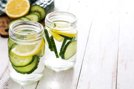 Detox water with cucumber and lemon on white wooden tableの写真素材