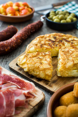 Traditional spanish tapas. Croquettes, olives, omelette, ham and patatas bravas on wooden tableの写真素材
