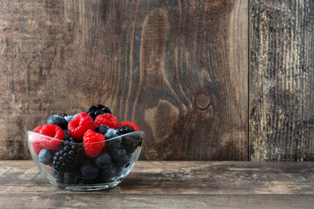 Healthy berries in glass bowl on wooden table
