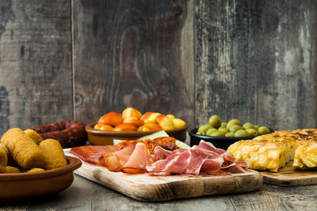Traditional spanish tapas. Croquettes, olives, omelette, ham and patatas bravas on wooden tableの写真素材