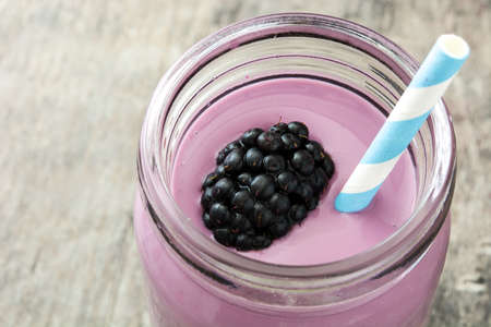 Healthy blackberry smoothie in glass on wooden tableの写真素材