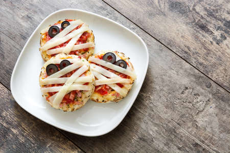 Halloween mummies mini pizzas on wooden table.Top viewの写真素材