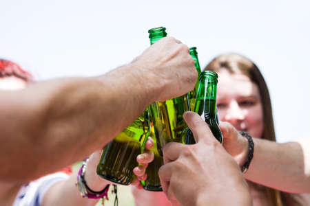 Picnic day with friends cheering with bottles of beerの写真素材