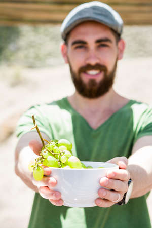 Young man showing grapes in bowlの写真素材