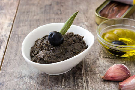 Black olive tapenade with anchovies, garlic and olive oil on wooden tableの写真素材