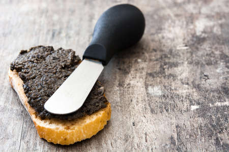 Black olive tapenade with anchovies, garlic and olive oil on wooden tableの写真素材