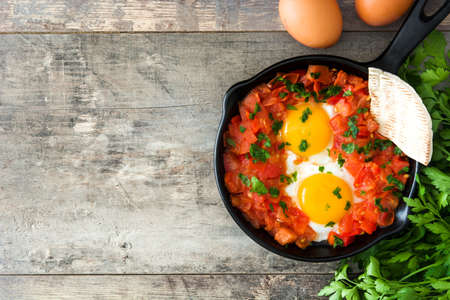Shakshuka in iron frying pan on wooden table. Typical food in Israel.の写真素材