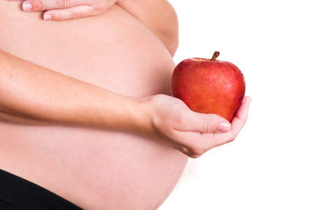 Pregnant woman with a red apple isolated on white backgroundの写真素材