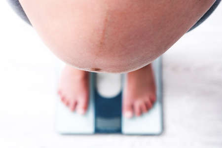 Pregnant woman standing on scalesの写真素材