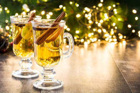 mulled cider in glass, ornaments and christmas light on wooden table