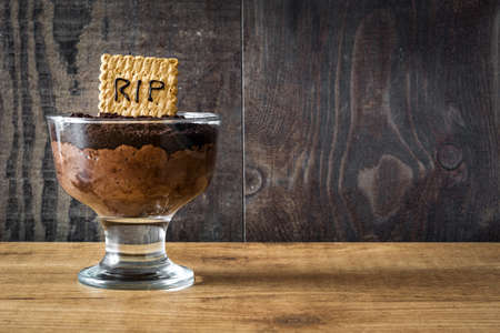 Funny Halloween chocolate mousse with tomb cookie on wooden tableの写真素材