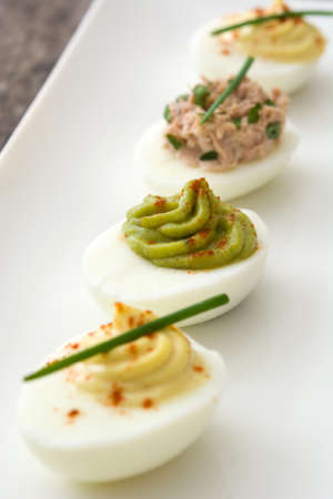 Variety of stuffed eggs with avocado and tuna on wooden tableの写真素材