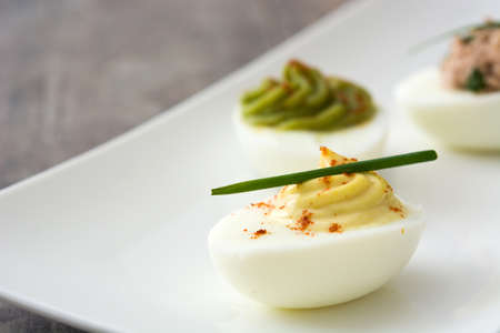 Variety of stuffed eggs with avocado and tuna on wooden table