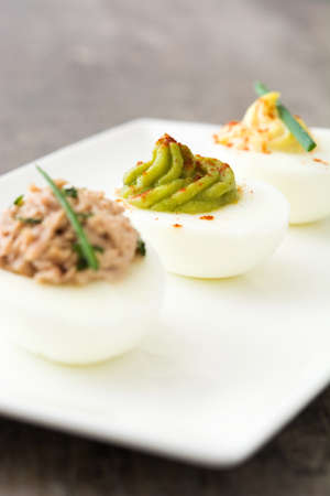 Variety of stuffed eggs with avocado and tuna on wooden tableの写真素材
