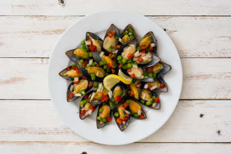 Steamed mussels with peppers and onion on white wooden table. Top viewの写真素材