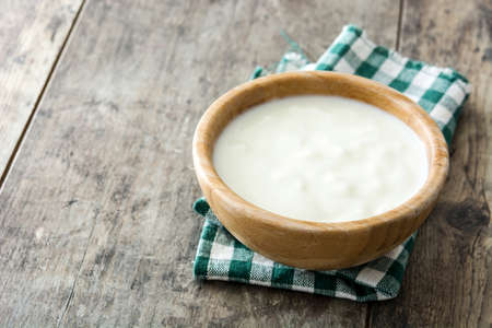 Natural yogurt in wooden bowl on wooden table. Copyspaceの写真素材