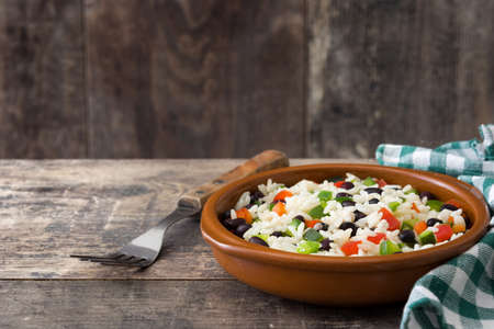 Traditional cuban rice, black beans and pepper on wooden table background. Moors and Christians.の写真素材