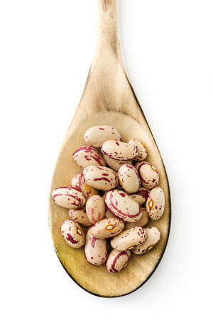 Raw pinto beans on wooden spoon isolated on white background