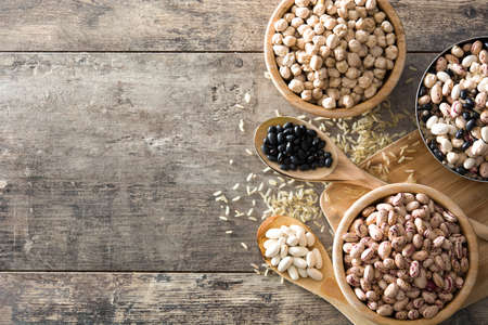 Uncooked assorted legumes in wooden bowl .Top view copy space on wooden table