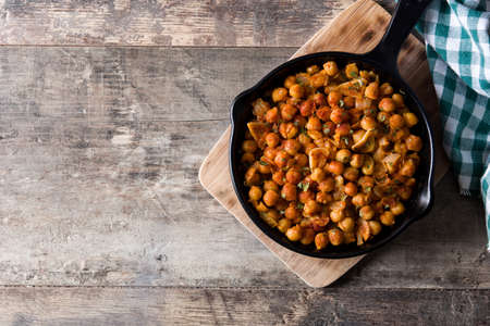 Fried spicy chickpeas in frying pan on wooden tableの写真素材