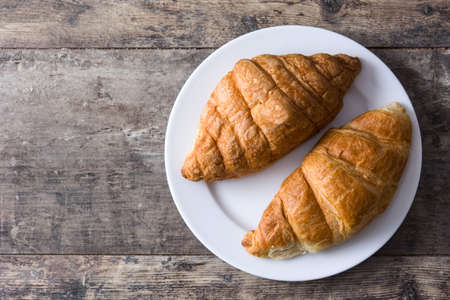 Croissant in plate on wooden table. Copyspaceの写真素材