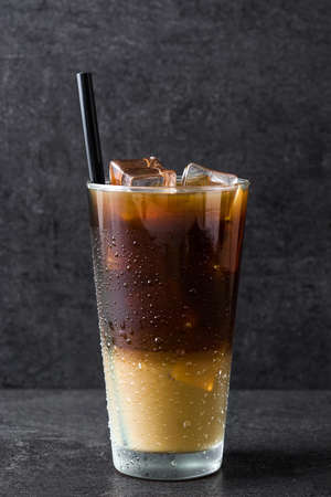 Iced coffee in glass on black stone