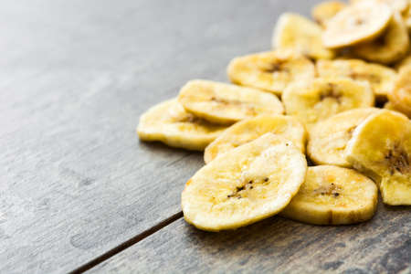 Banana chips on wooden table. Copyspaceの写真素材
