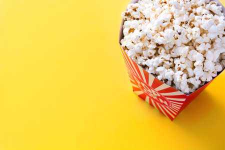 Striped box with popcorn on yellow background. Copyspaceの写真素材