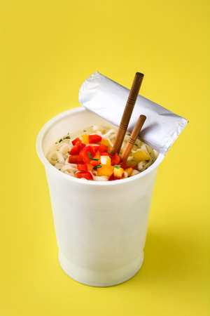 Take away noodles with vegetables on yellow backgroundの写真素材