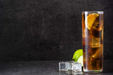 Cuba libre. Cocktail with rum, lime and ice on black stone. Copyspaceの写真素材