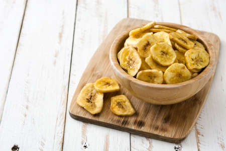 Banana chips in bowl on white wooden table. Copyspaceの写真素材