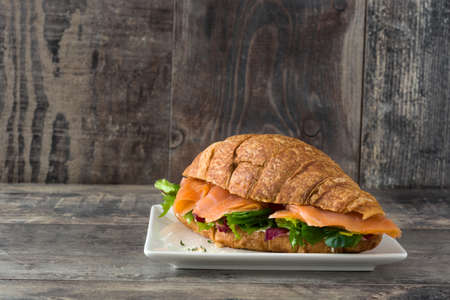 Croissant sandwich with salmon and vegetables on wooden tableの写真素材