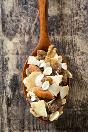 Muesli and dried fruit in wooden spoon on wooden table. Top view