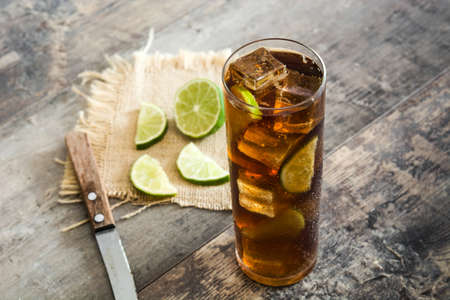 Cuba libre. Cocktail with rum, lime and ice on wooden tableの写真素材