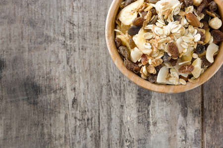 Muesli and dried fruit in wooden bowl on wooden table. Top view Copyspaceの写真素材