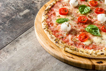 Pizza with tomatoes, cheese and basil on wooden table.Copyspaceの写真素材
