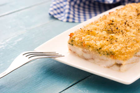 White fish casserole with cheese on blue wooden background.の写真素材