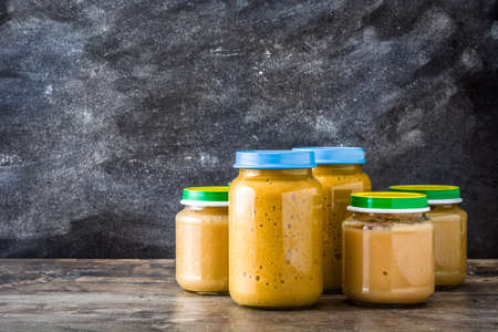 Baby food: Jar with fruit puree on wooden table. Copyspaceの写真素材