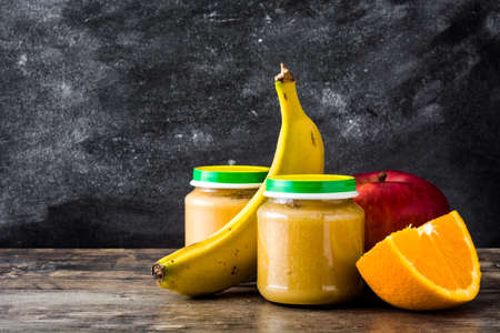 Baby food: Jar with fruit puree on wooden table. Copyspaceの写真素材