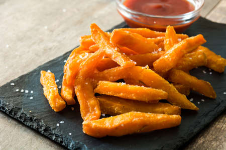 Sweet potato fries and ketchup sauce on wooden tableの写真素材
