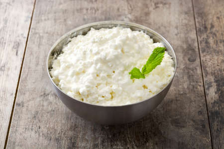 Fresh cottage cheese in a metal bowl on wooden tableの写真素材