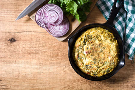 Frittata made of eggs and vegetables in a pan, on wooden table. Top view Copyspaceの写真素材