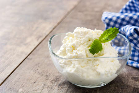 Fresh cottage cheese in a glass bowl on wooden table. Copyspaceの写真素材