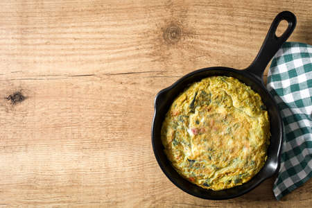 Frittata made of eggs and vegetables in a pan, on wooden table. Top view Copyspaceの写真素材