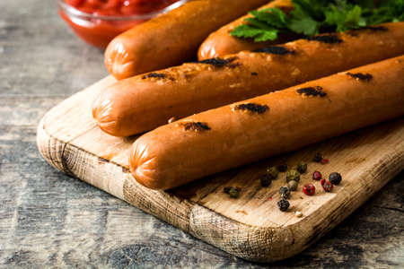 Grilled sausages and ketchup on wooden tableの写真素材