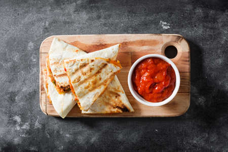 Mexican quesadilla with chicken, cheese and peppers on black slate. Top view