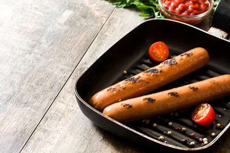 Grilled sausages and ketchup on wooden tableの写真素材