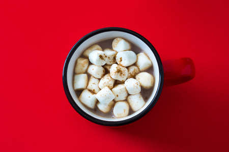 Christmas cocoa with marshmallow in mug on red background. Top view.