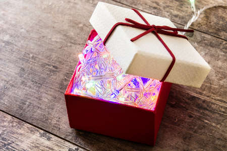 Christmas light in red gift box on wooden table